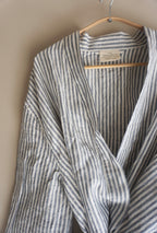 A 100% French Flax linen dressing gown hanging on a wooden coat hanger, in  Marine Stripe by Simple Linen Co.