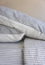 Simple Linen Co. 100% French flax linen double sided duvet cover set Ida in Charcoal Stripe and Double pinstripe, paired with Nature sheet, sustainably packaged in reusable linen drawstring bag, stonewashed for softness and breathable year-round comfort.