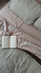 Simple Linen Co. 100% French flax linen sheet set in Light pink, featured with Liv, Olive and Olive Stripe double sided duvet cover set, top down view of bed with an open book.
