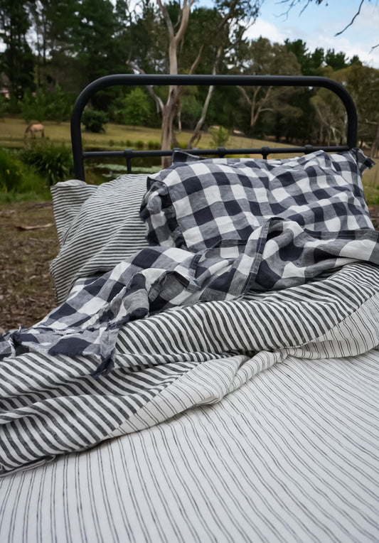 Simple Linen Co. 100% French flax linen ruffle edged sheet set in Night Blue Grids,  in outdoor farm setting.